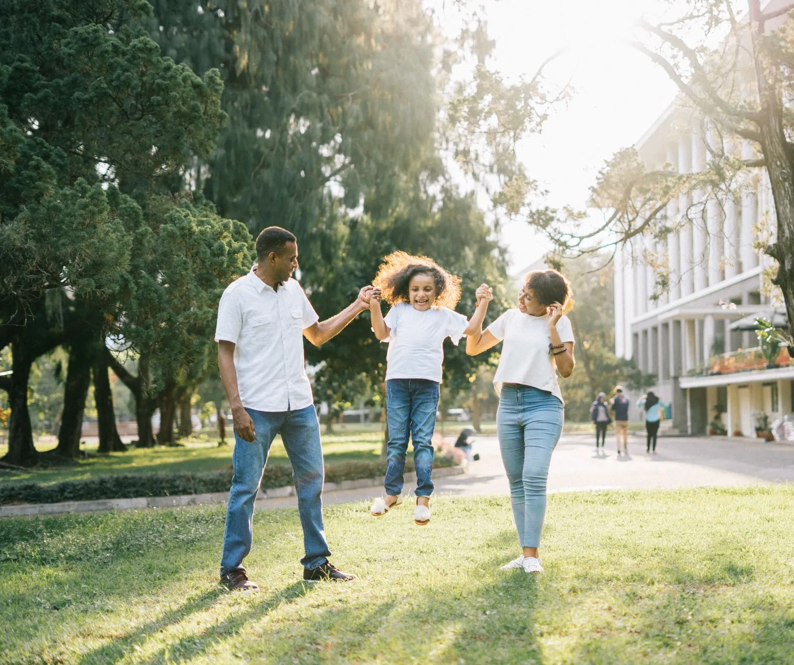 Family walking in a park holding their daughter’s hands