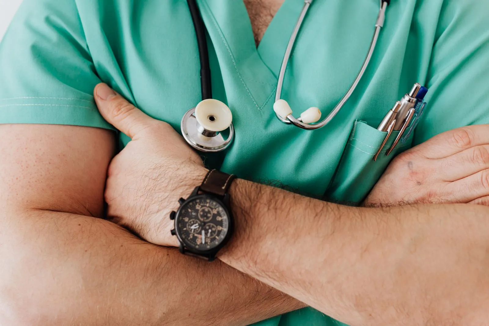 Doctor in scrubs with a stethoscope and arms crossed