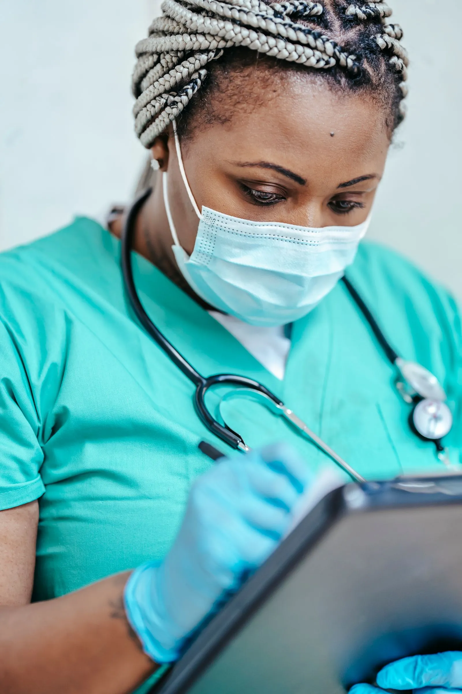 Nurse in scrubs and a face mask using a tablet